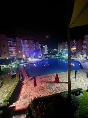 a large swimming pool in a city at night at residence al kawtar in Mansouria