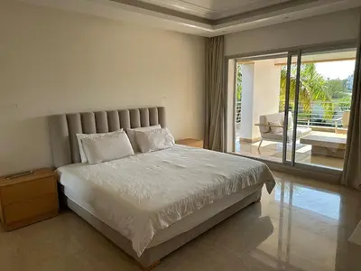 a bedroom with a large bed and a balcony at Bouznika Bay Villa Prestigious Oasis in Sidi el Haj Bou Derbala