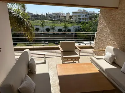 a balcony with couches and a table and chairs at Bouznika Bay Villa Prestigious Oasis in Sidi el Haj Bou Derbala