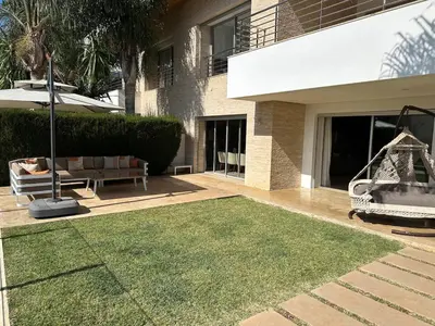 a patio with a lawn and a swing and a house at Bouznika Bay Villa Prestigious Oasis in Sidi el Haj Bou Derbala