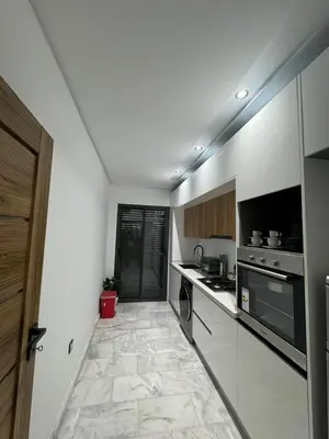 a kitchen with white walls and a tile floor at Appartement VictoriaBouskoura in Casablanca