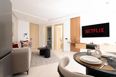 a living room with a dining table and ametix sign on the wall at Modern & bright studio Balcony & Parking Maarif in Casablanca