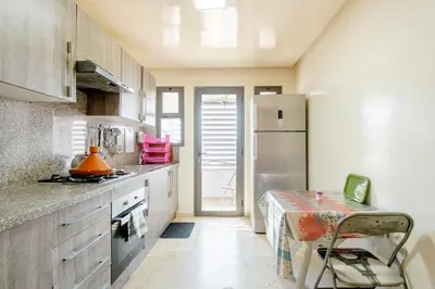 a kitchen with a refrigerator and a table in it at Comfort Stay by Mohammed V Airport in Nouaseur