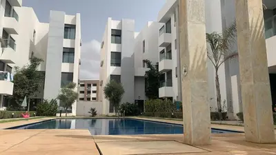 a swimming pool in front of a building at Appartement avec une Chambre, Salon, Salle de Bain et Piscine in El Harhoura