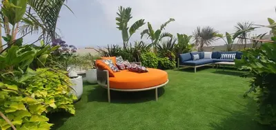 an orange ottoman sitting on the grass in a garden at Studio moderne rooftop et gym Triangle d or casablanca in Casablanca