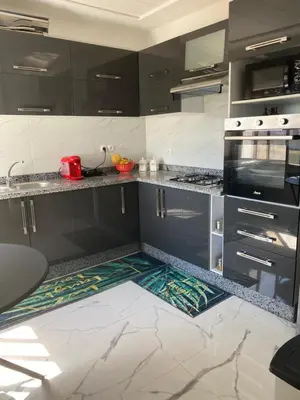 a kitchen with black cabinets and marble flooring at Jnane in Sidi Rahal