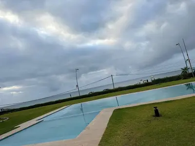 a large swimming pool with the ocean in the background at Appartement à Dar bouaaza in Tamaris