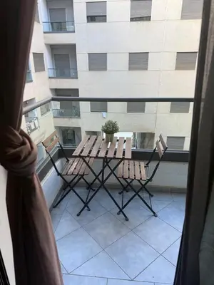 a table and chairs on a balcony with a building at Appartement de lux avec piscine in Mohammedia