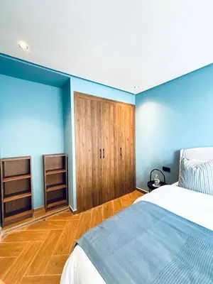 a bedroom with blue walls and a bed and wooden floors at Luxury 1-Bedroom Apartment in Maarif in Casablanca