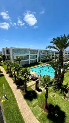a large building with a large swimming pool with palm trees at Ramoflores , sidi rahal in Sidi Rahal