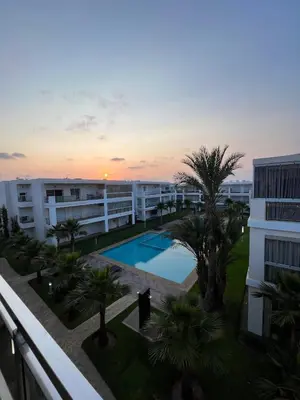 a view of a building with a pool and palm trees at Ramoflores , sidi rahal in Sidi Rahal