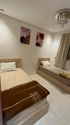 a bedroom with two beds and paintings on the wall at appart 206 in Temara