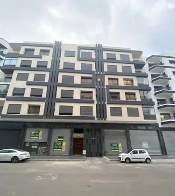 two cars parked in front of a large building at Appt 1 ch meublé CFC TO CLOSE in Casablanca