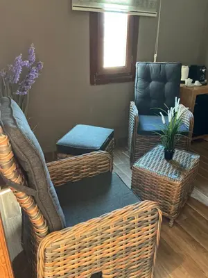 a living room with wicker chairs and a chair and a table at Palm Palace Bouznika in Bouznika