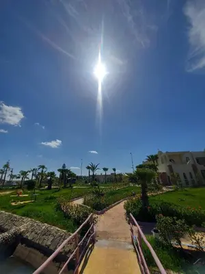 a sun shining in the sky over a path at Palm Palace Bouznika in Bouznika