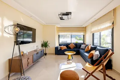 a living room with a blue couch and some windows at Charming Villa in Harhoura in Temara