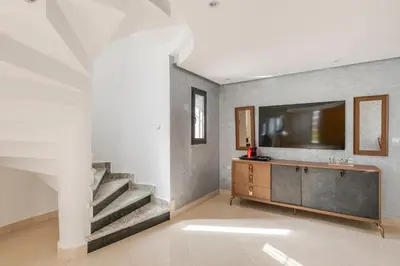 a living room with a staircase and a television on a wall at Charming Villa in Harhoura in Temara
