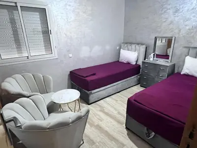 a bedroom with two beds and chairs and a mirror at Beachfront apartment in Rabat