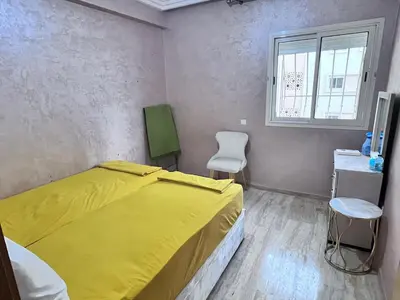 a bedroom with a yellow bed and a chair at Beachfront apartment in Rabat