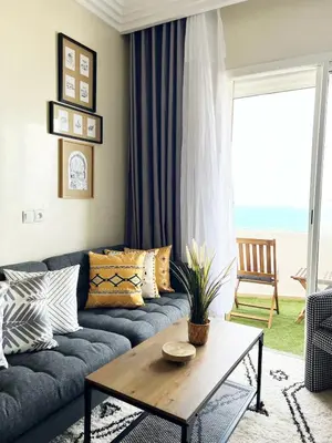 a living room with a blue couch and a table at Ocean view & sunset in the heart of Rabat 2 in Rabat