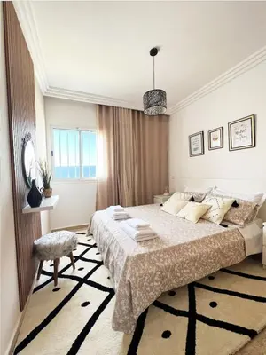 a white bedroom with a large bed and a window at Ocean view & sunset in the heart of Rabat 2 in Rabat