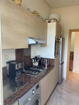 a kitchen with a stove top oven next to a refrigerator at CASABAY Sidi Rahal, appartement avec accès direct à la piscine in Sidi Rahal