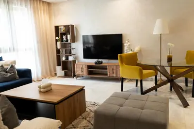 a living room with a television and a table and chairs at Prime location unmatched comfort in Casablanca