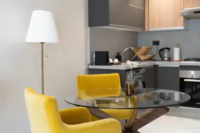 a kitchen with a glass table and yellow chairs at Prime location unmatched comfort in Casablanca