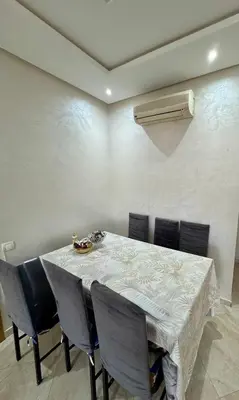 a dining room with a table with chairs and a heater at Les Jardins de Bouznika Premium - Votre espace familial in Bouznika