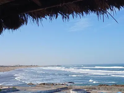 a view of the beach from a straw umbrella at Bienvenue à Casablanca centre idéal pro ou famille in Casablanca