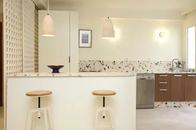 a white kitchen with two stools at a counter at Cozy apartment 5 minutes from Casa Voyageurs in Casablanca