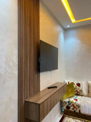 a room with a television on a wall with a couch at Appartement meublé a sidi rahal in Sidi Rahal