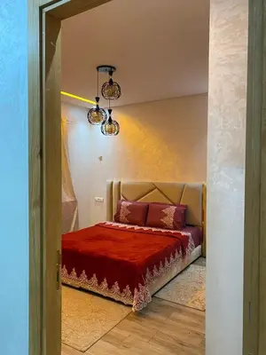 a bedroom with a bed with a red blanket at Appartement meublé a sidi rahal in Sidi Rahal