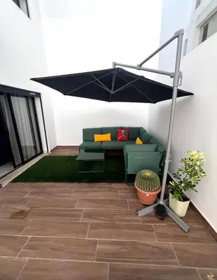 a patio with a couch under a black umbrella at Great for families and couples in Casablanca