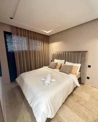 a bedroom with a large white bed with a headboard at Beautiful apartment in Tadart in Casablanca