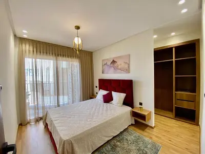 a bedroom with a large bed and a large window at Très beau appartement a tadart au centre de casablanca in Casablanca