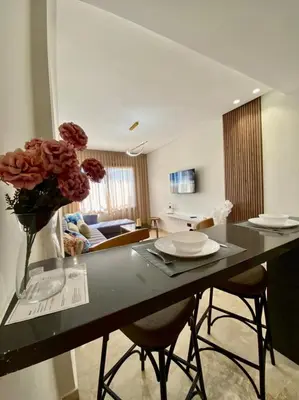 a kitchen with a table with a vase of flowers at Très beau appartement a tadart au centre de casablanca in Casablanca