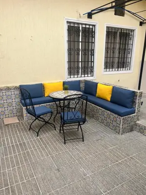 a blue couch with yellow pillows sitting next to a table at Maison traditionnelle spacieuse in Rabat