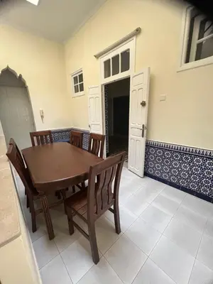 a dining room with a wooden table and chairs at Maison traditionnelle spacieuse in Rabat