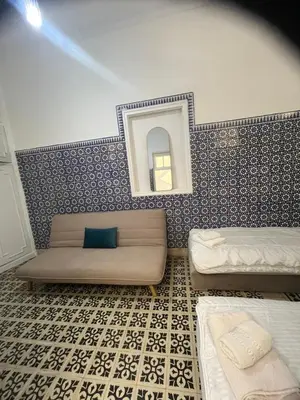 a room with two beds and a mirror on a wall at Maison traditionnelle spacieuse in Rabat