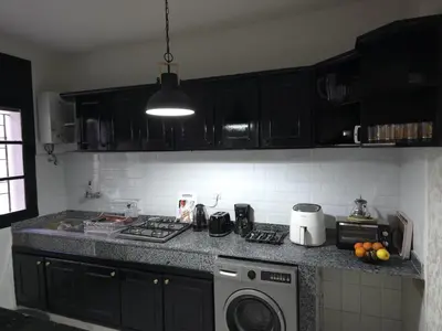 a kitchen with black cabinets and a washing machine at Faridi house in Casablanca