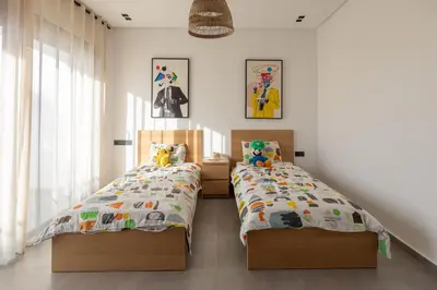 two beds in a bedroom with white walls at Beach Vibe Villa - Sunny Stay in O Ben Slimane