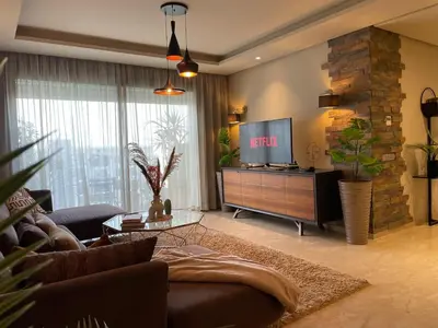 a living room with a couch and a flat screen tv at Cozy Boho 2BR Prestigia Stadium View in Rabat