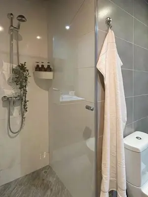 a bathroom with a glass shower with a toilet at Cozy Boho 2BR Prestigia Stadium View in Rabat