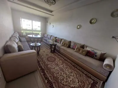 a living room with a long couch and a table at Appartement avec piscine in Mohammedia