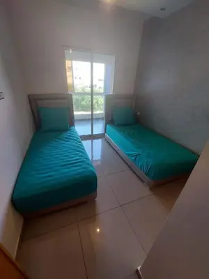 two green beds in a room with a window at Appartement avec piscine in Mohammedia
