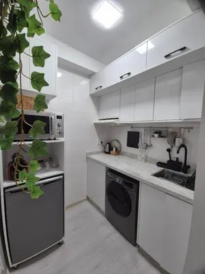 a kitchen with white cabinets and a black dishwasher at Studio close to Descartes high school in Rabat