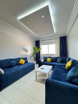a living room with a blue couch and a table at SUITOUISS - Océan 2 - Panoramic Sea View in Downtown Rabat in Rabat