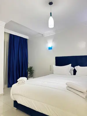 a bedroom with a large white bed with blue curtains at SUITOUISS - Océan 2 - Panoramic Sea View in Downtown Rabat in Rabat