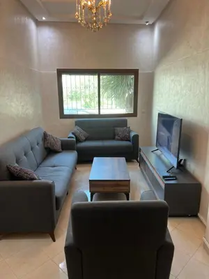 a living room with a couch and a tv at Steps to the beach in Sidi Rahal